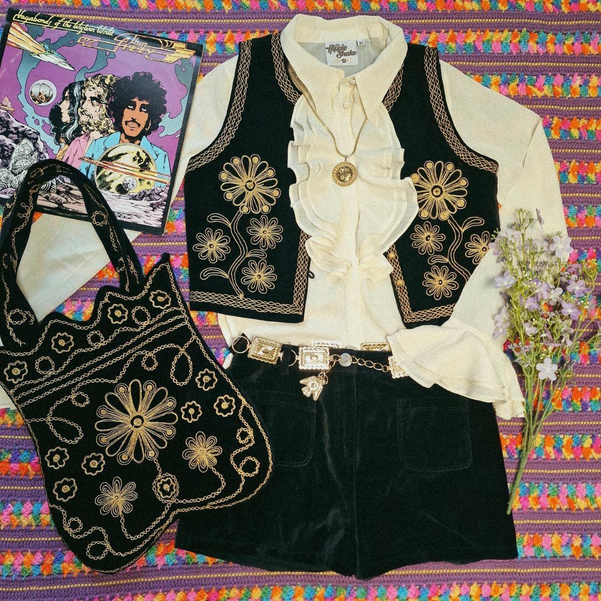 70s Inspired Outfits with 22 Groovy Looks to Try Now 17 Flat lay of a 70s style outfit with embroidered black velvet vest, blouse, shorts, and bag.