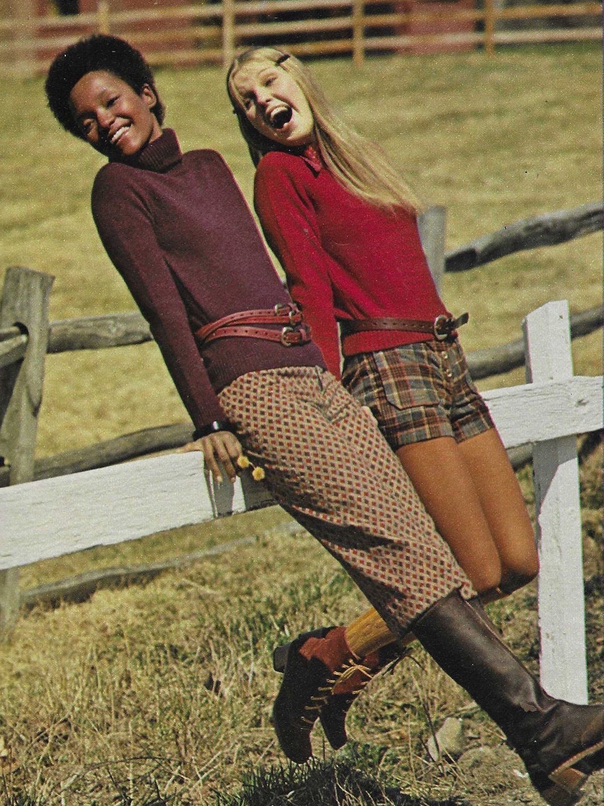 70s Inspired Outfits with 22 Groovy Looks to Try Now 12 Two women in retro 1970s fashion posing outdoors by a white wooden fence.