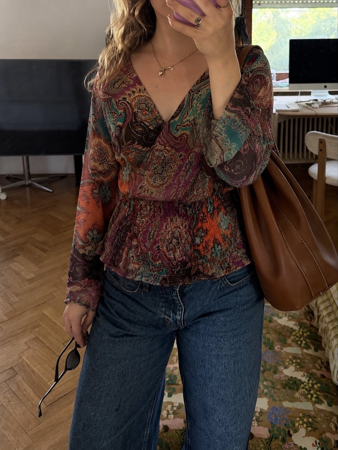 70s Inspired Outfits with 22 Groovy Looks to Try Now 7 A person wearing a colorful paisley print peasant top and blue denim jeans.
