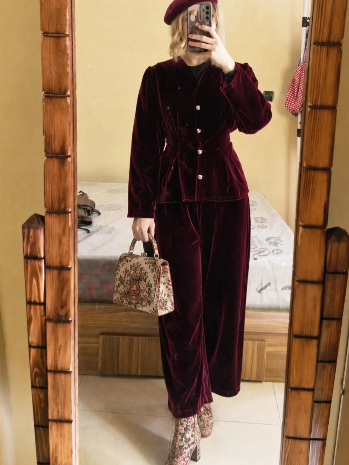 Person in a red velvet suit with a matching beret and floral handbag.