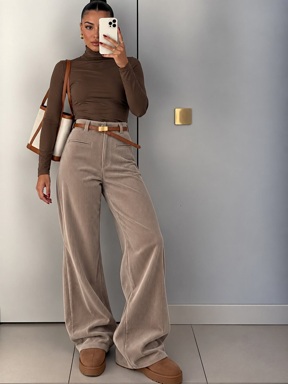 5 All Brown Outfit Ideas to Refresh Your Wardrobe 1 Woman in brown turtleneck and wide-leg brown corduroy pants taking a mirror selfie.