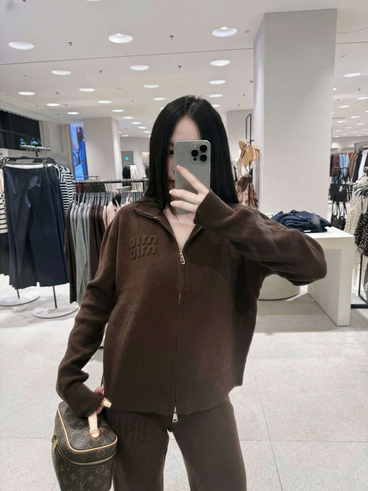5 All Brown Outfit Ideas to Refresh Your Wardrobe 5 Person in a brown matching knit set holding a brown patterned handbag in store