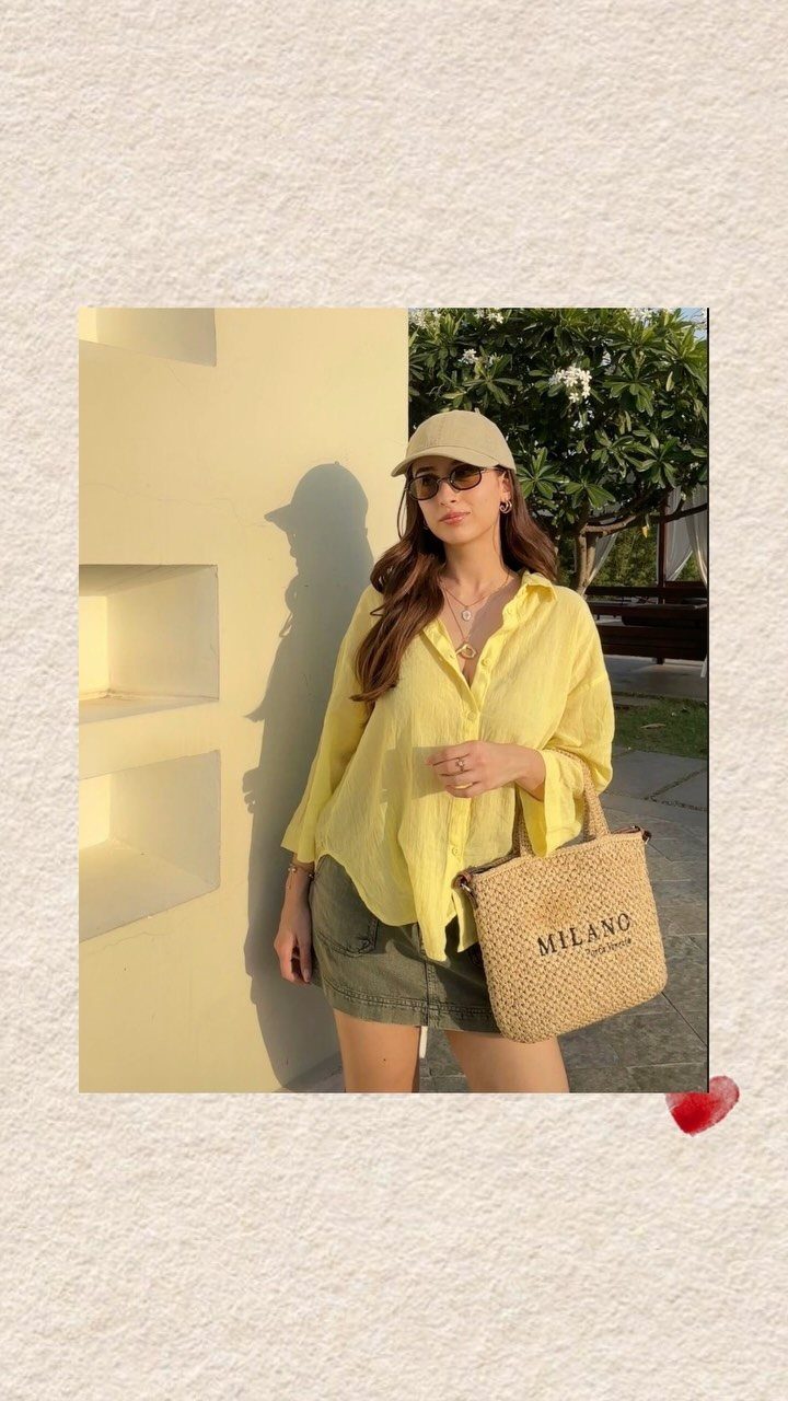 Beach Vacation Outfits: 9 Ideas for Easy Packing 5 Woman in a yellow shirt and sunglasses holding a large straw tote bag outdoors.