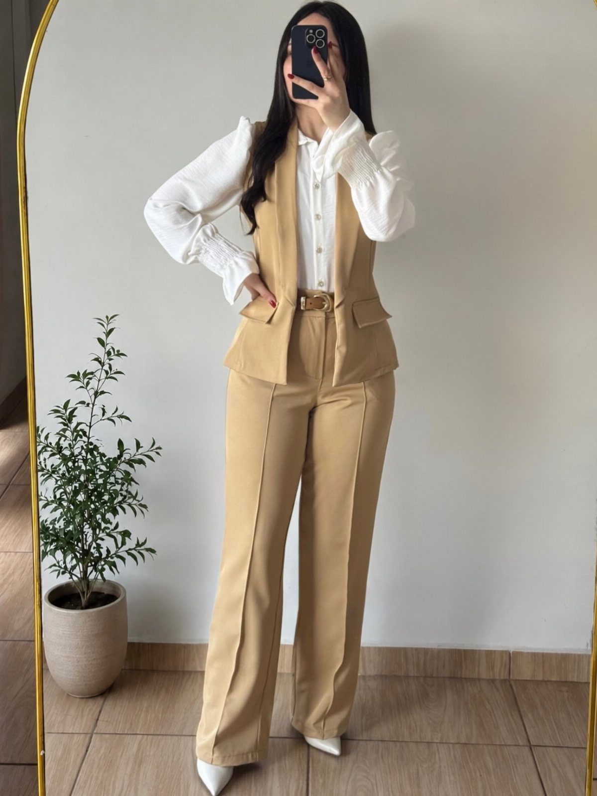 Woman wearing a beige vest and matching wide-leg trousers with a white shirt.