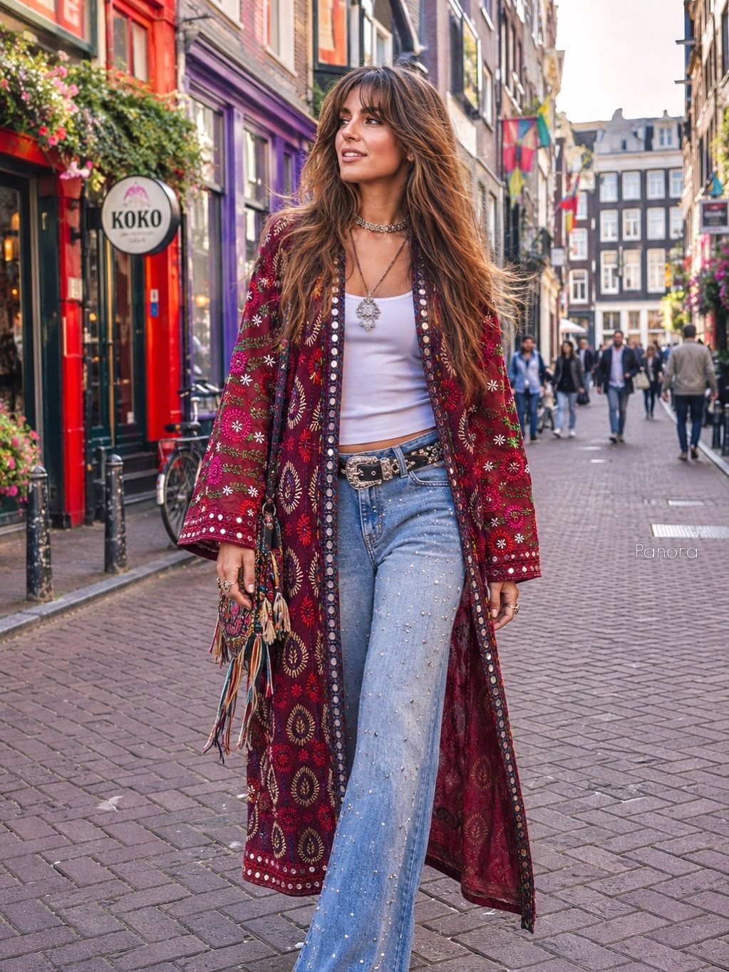 Woman walking in a city street wearing a long red patterned kimono and flared jeans.