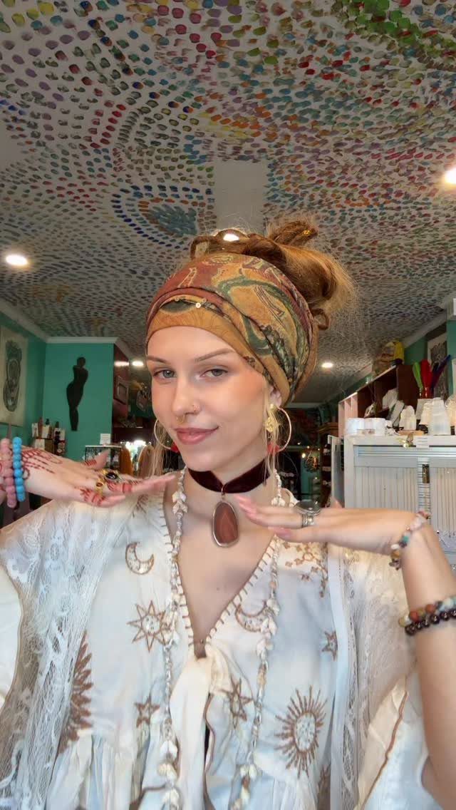 Woman wearing a bohemian outfit with a patterned headscarf and celestial embroidered white blouse.