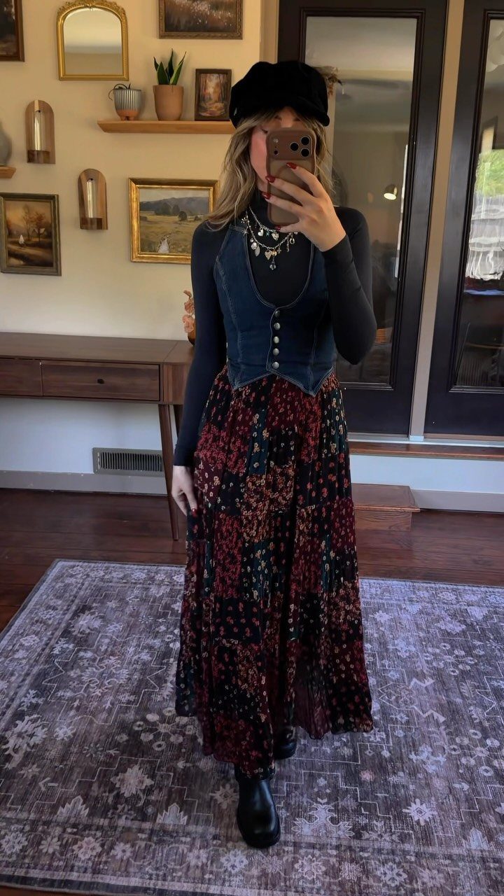 Woman in a boho style outfit featuring a denim vest and long floral skirt posing for a selfie.