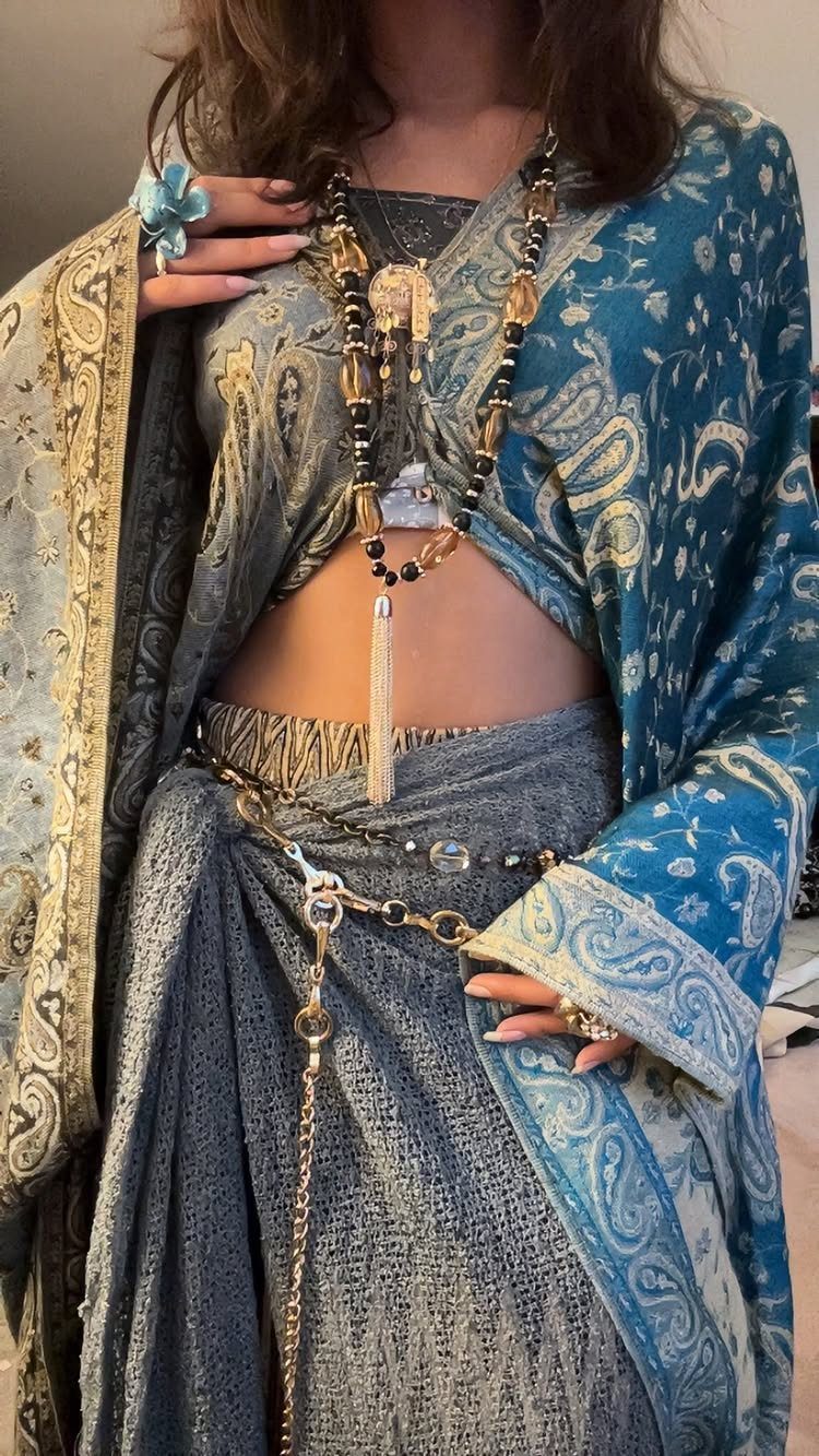 Woman wearing blue paisley kimono with layered beaded necklaces and a metallic waist chain.