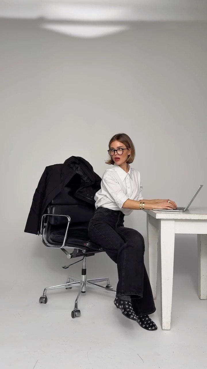 Business Casual Outfits for Work: 8 Polished Ideas 5 Woman in a white shirt and black trousers working on a laptop at a white desk.