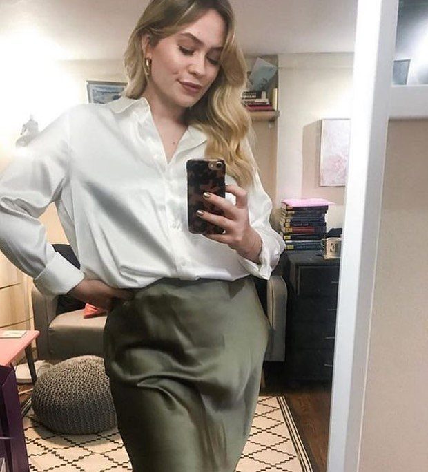 Business Casual Outfits for Work: 8 Polished Ideas 7 Woman in a white button-down shirt and olive green satin skirt posing for a mirror selfie.