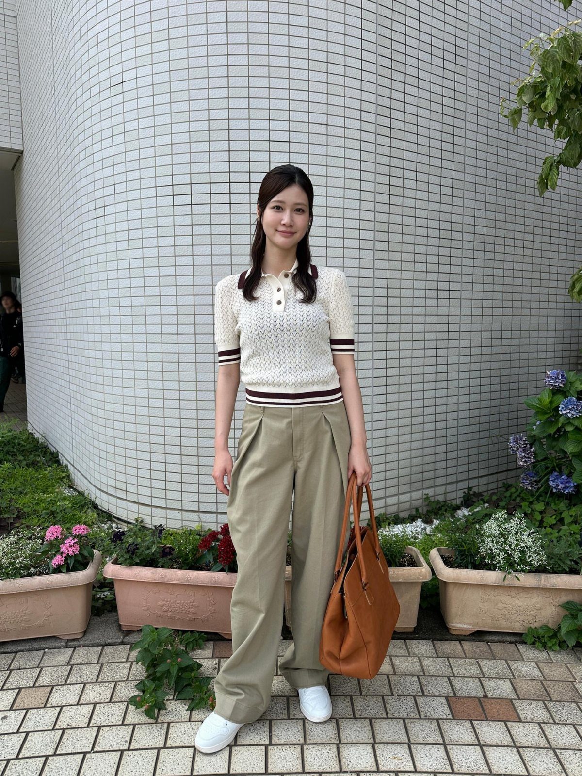 Woman wearing a white knit polo, khaki wide-leg trousers, and white sneakers outdoors.