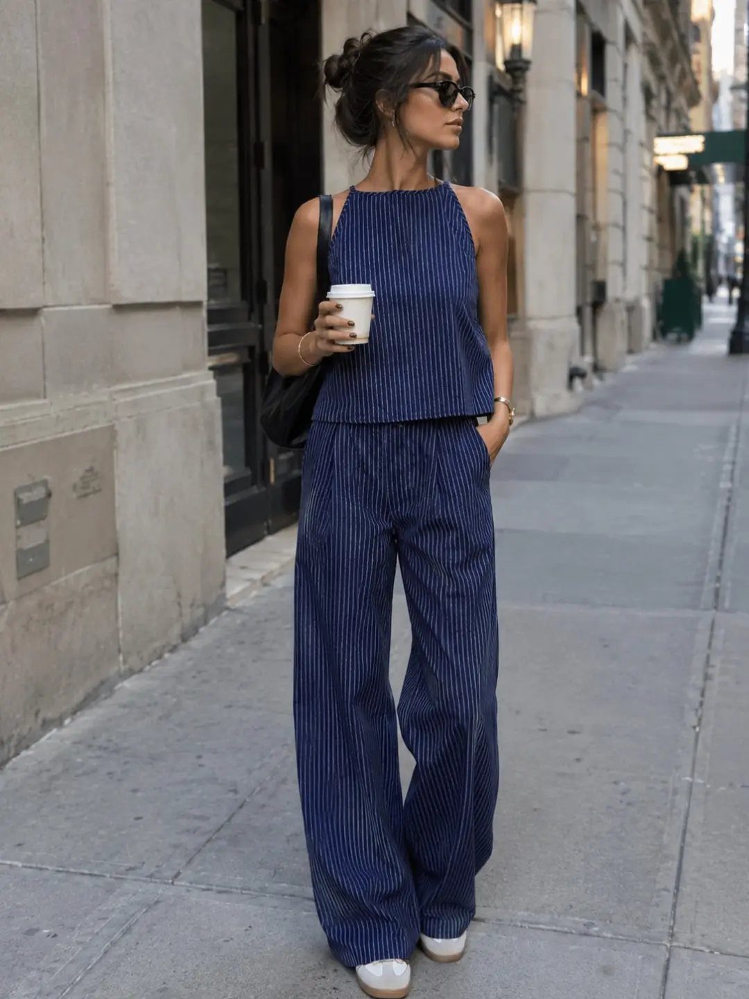Woman in navy blue pinstripe matching set with wide-leg trousers on a city street.