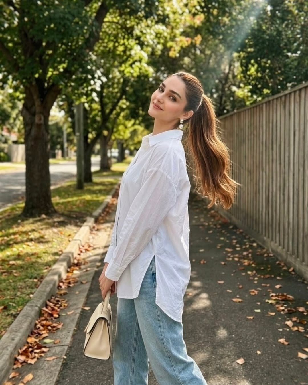 Woman wearing an oversized white button-down shirt and light blue wide-leg jeans outdoors.