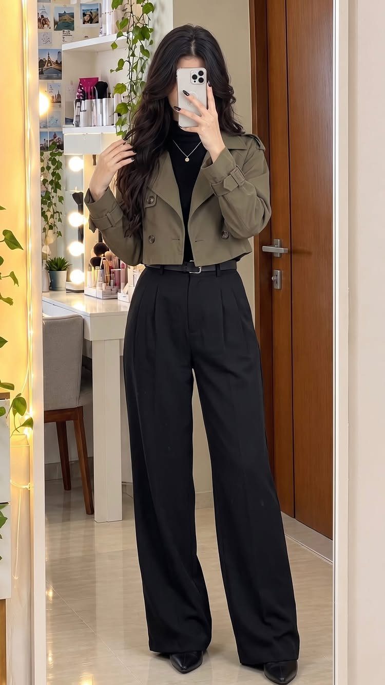 Woman wearing black wide-leg trousers and a cropped olive green jacket in a mirror selfie.