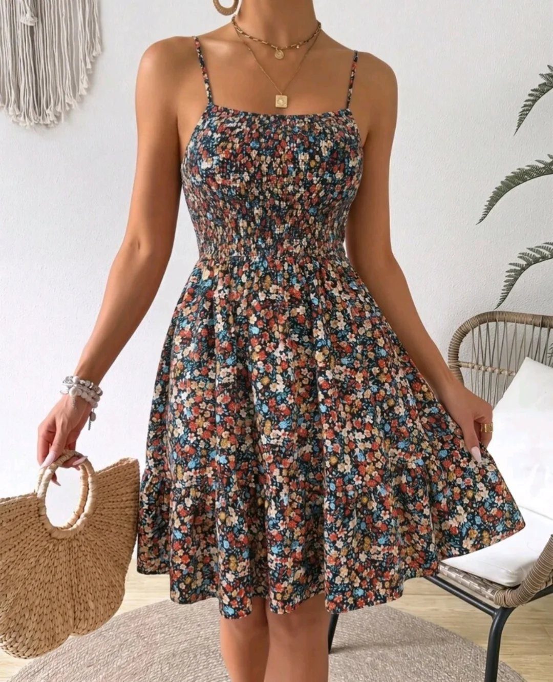 Woman wearing a short floral print sundress and holding a straw handbag.