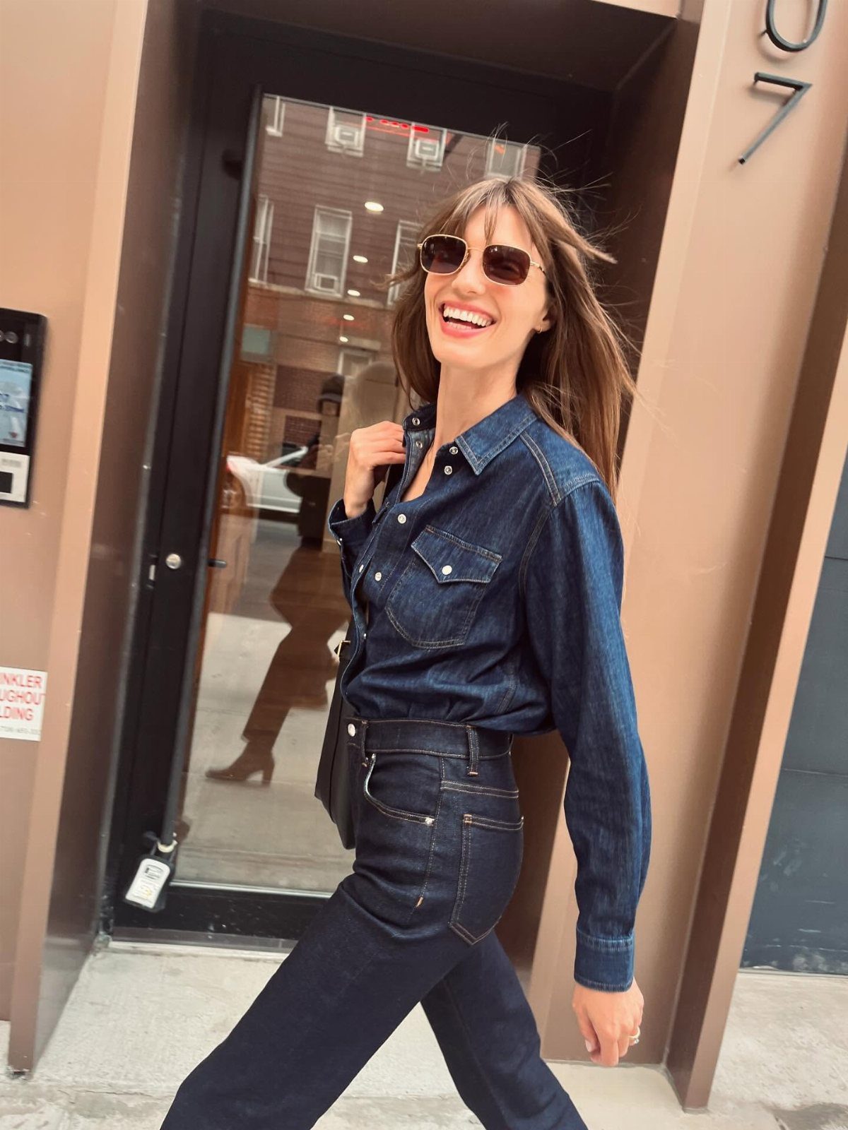 Woman wearing a dark blue denim shirt and matching dark blue jeans.