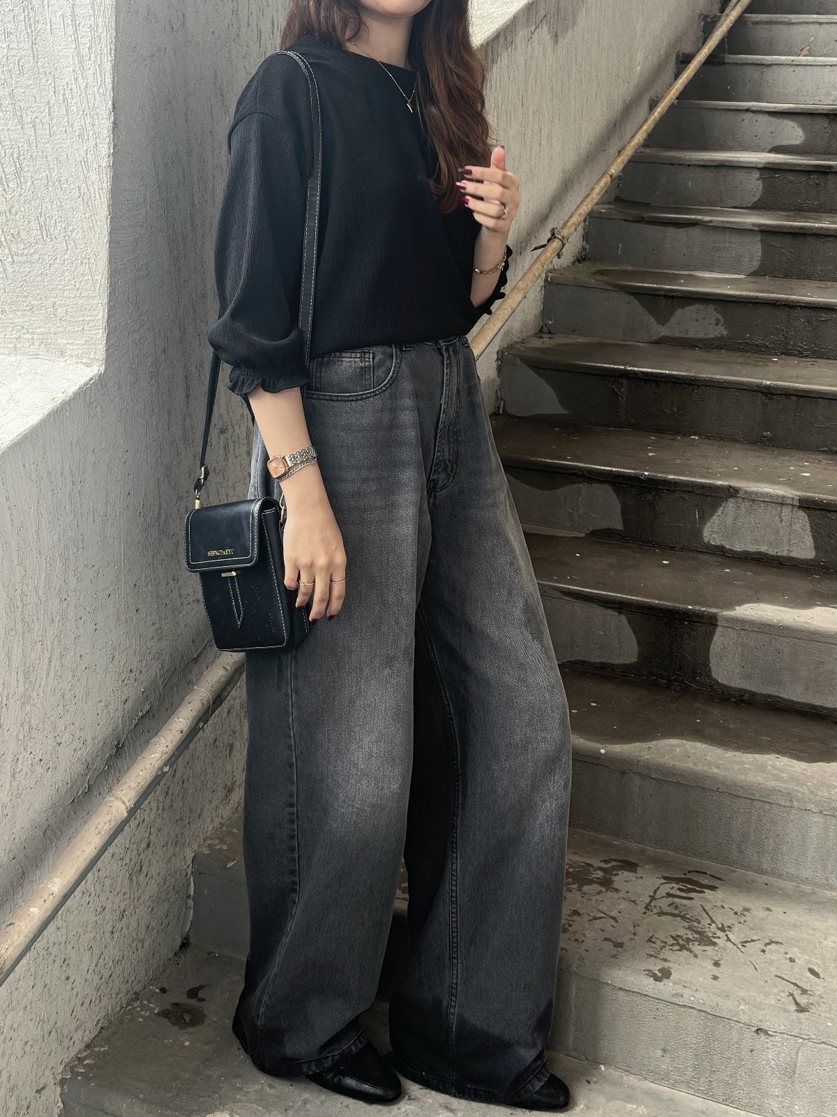 Casual Street Style: 8 Outfit Ideas for Women 1 Person wearing oversized black sweater and baggy grey jeans on concrete stairs