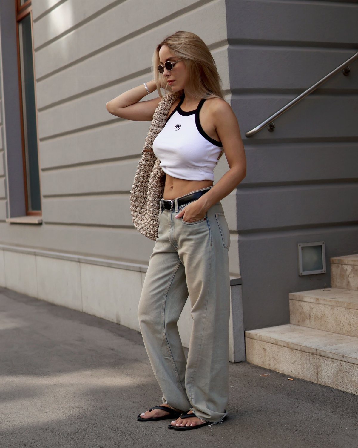 Casual Street Style: 8 Outfit Ideas for Women 3 Woman wearing a white cropped tank top and light grey wide-leg jeans.