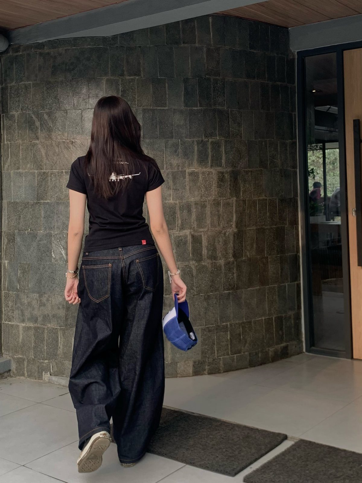 Casual Street Style: 8 Outfit Ideas for Women 2 Woman from behind wearing a black t-shirt and wide-leg dark blue denim jeans.