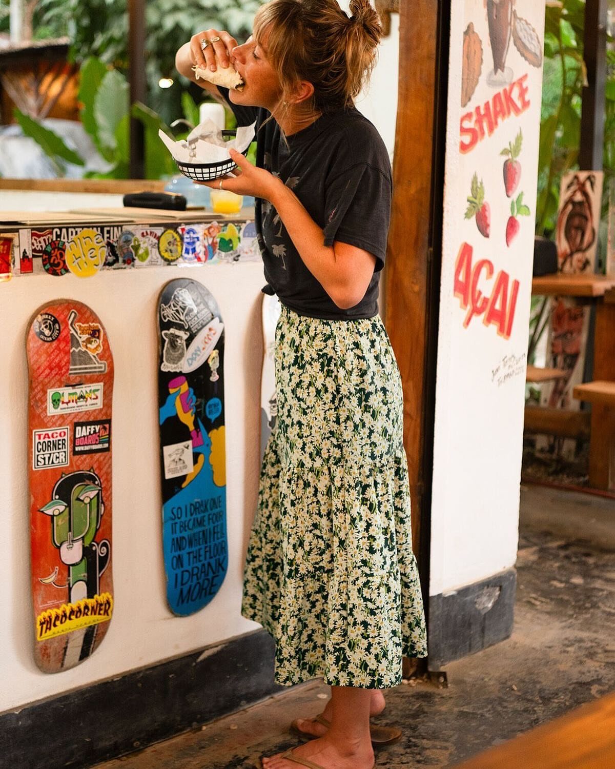 Casual Summer Outfits: 10 Easy Ideas for Daily Wear 4 Woman wearing a black t-shirt and a floral midi skirt eating food outdoors.