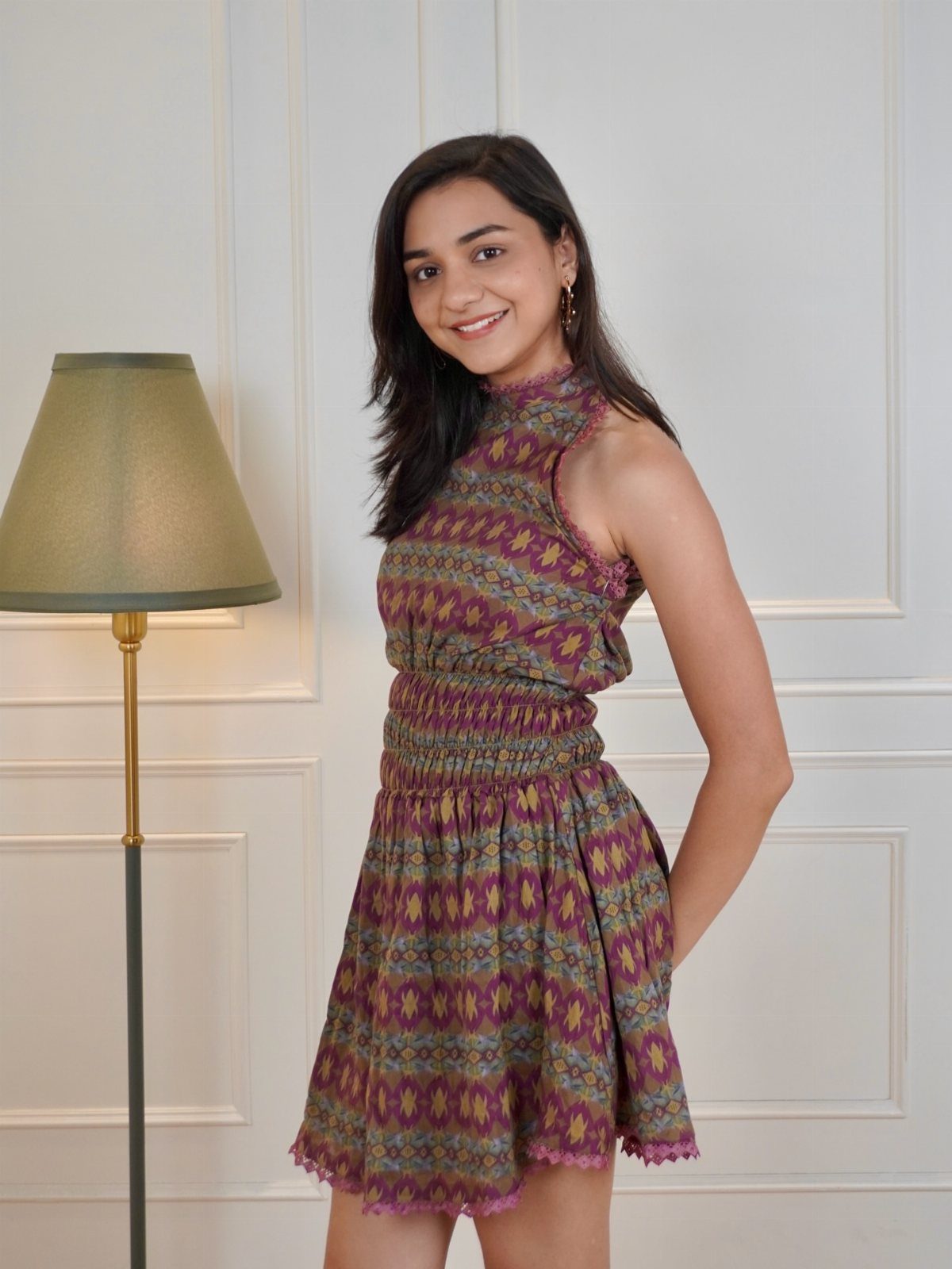 Casual Summer Outfits: 10 Easy Ideas for Daily Wear 2 A smiling young woman wearing a short, patterned sleeveless sundress standing indoors.