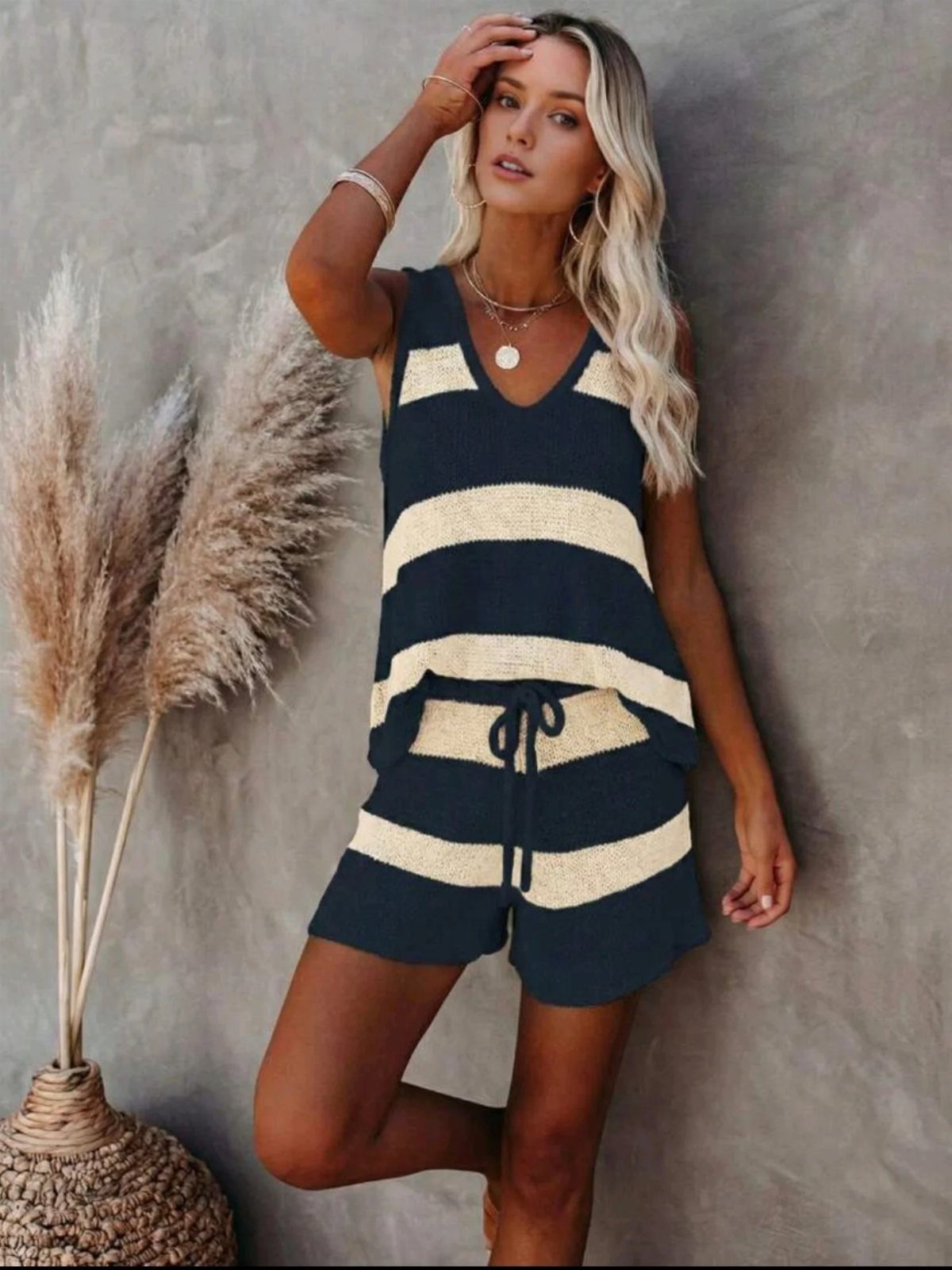 11 Casual Travel Outfit Ideas for Women (2026) 6 Woman wearing a navy and cream striped sleeveless knit top and matching shorts.