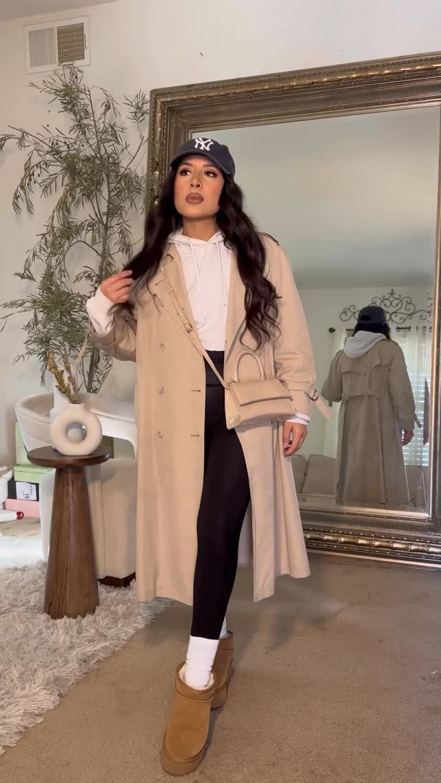 Chic Travel Outfits for Women: 14 Stylish Ideas for 2026 4 Woman in beige coat and black leggings posing in front of a mirror
