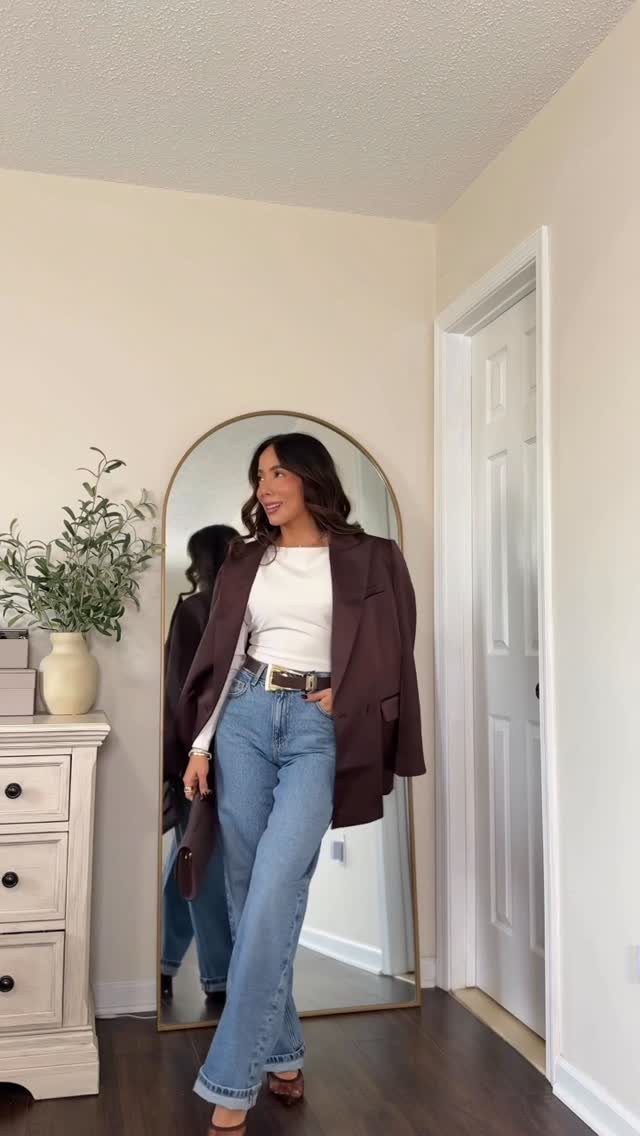 26 Classy Date Outfits From Casual to Elegant 5 Woman wearing a brown blazer and light blue jeans posing by an arched mirror.