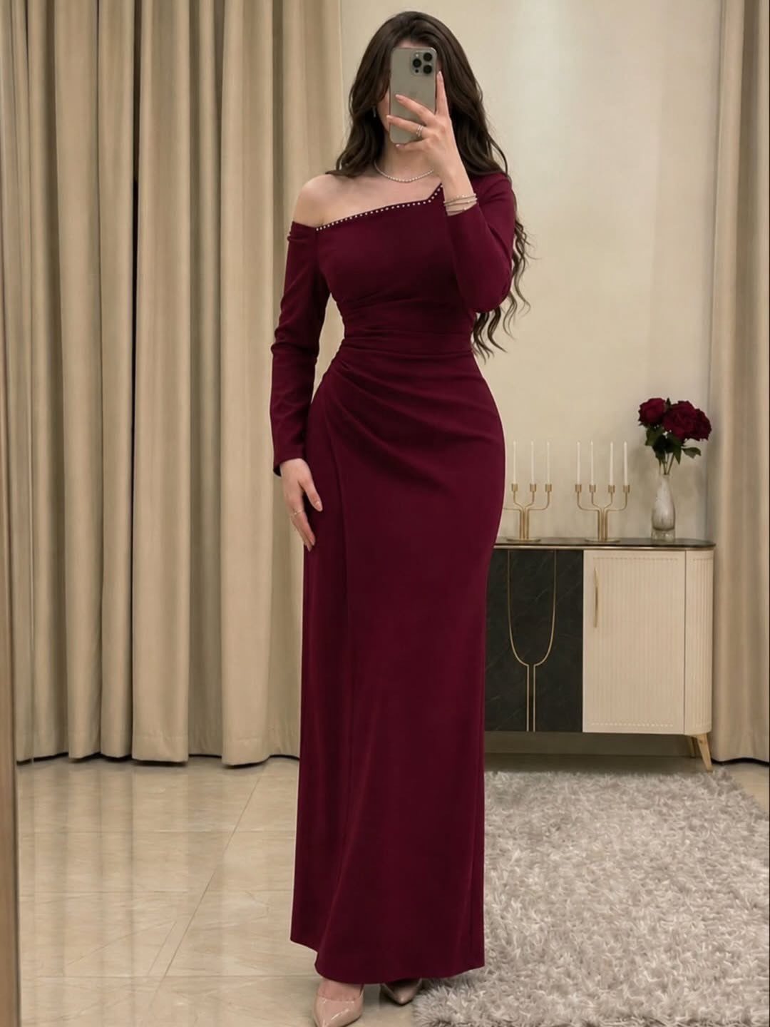26 Classy Date Outfits From Casual to Elegant 4 Woman in a long, form-fitting burgundy off-the-shoulder dress posing in a modern room.