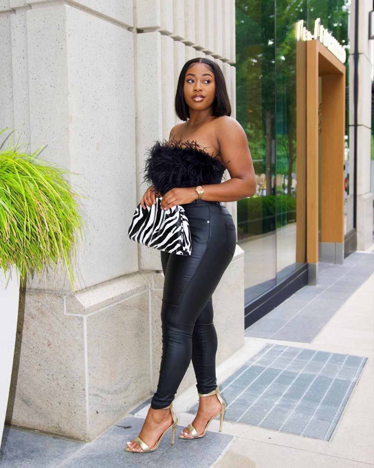 26 Classy Date Outfits From Casual to Elegant 25 Woman in black strapless top and leather leggings holding a zebra print clutch.