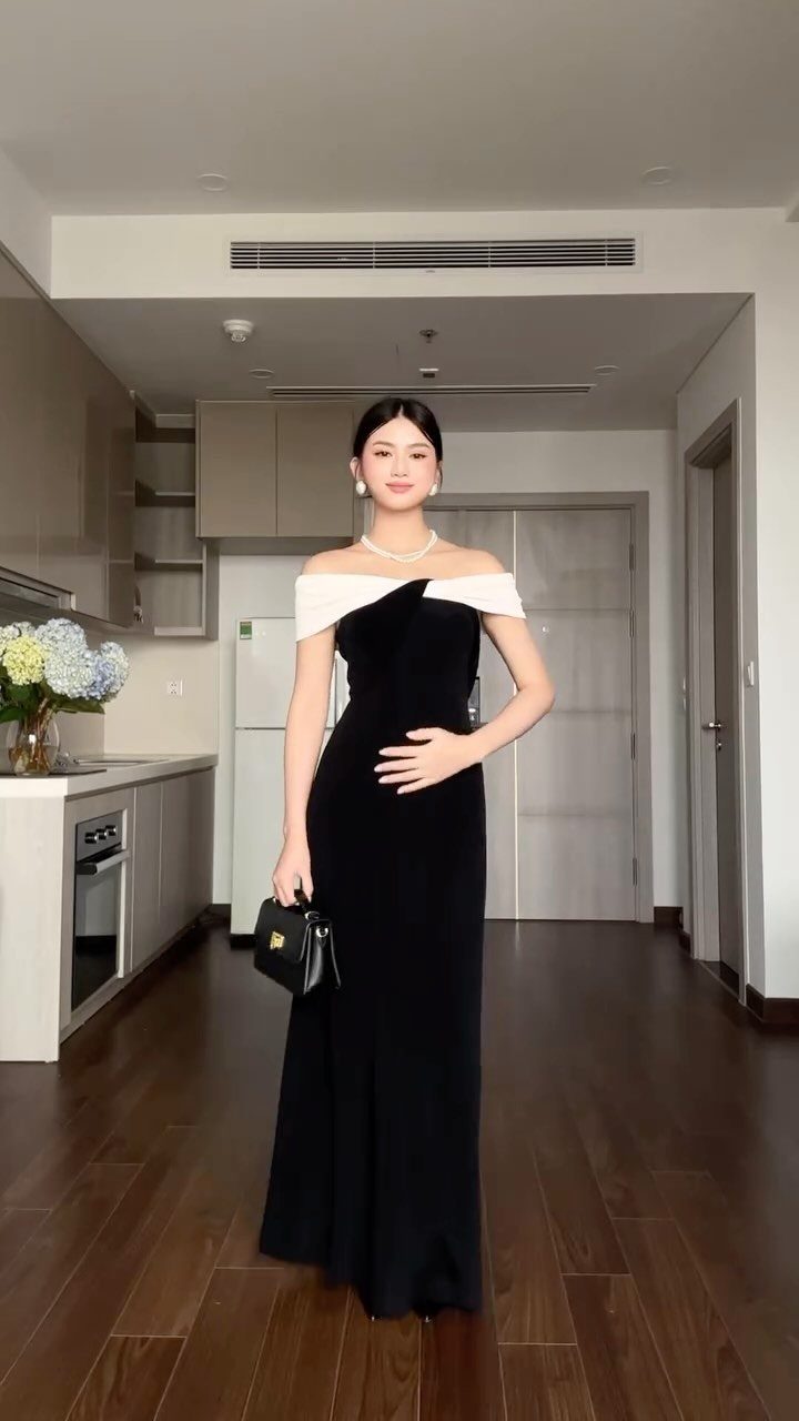 26 Classy Date Outfits From Casual to Elegant 17 Woman in a black off-shoulder statement dress with white detail and a pearl necklace.