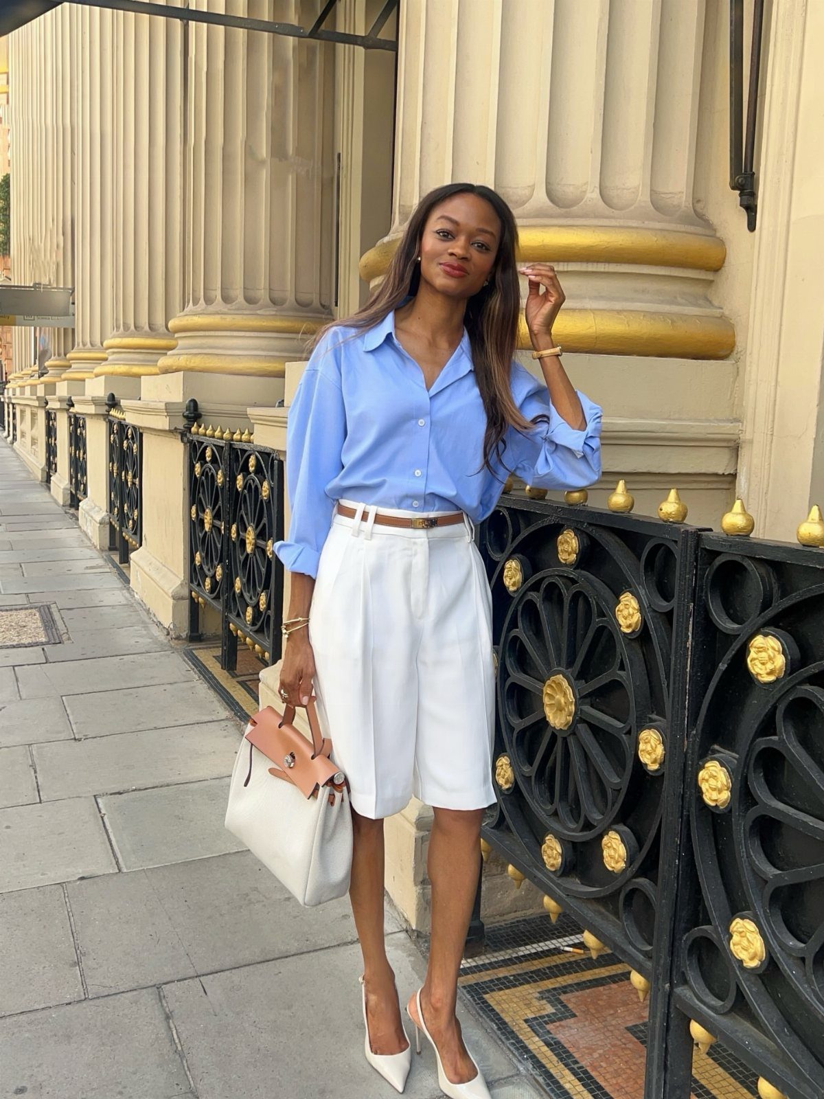 26 Classy Date Outfits From Casual to Elegant 8 Woman in light blue shirt and white tailored shorts posing on a city street.