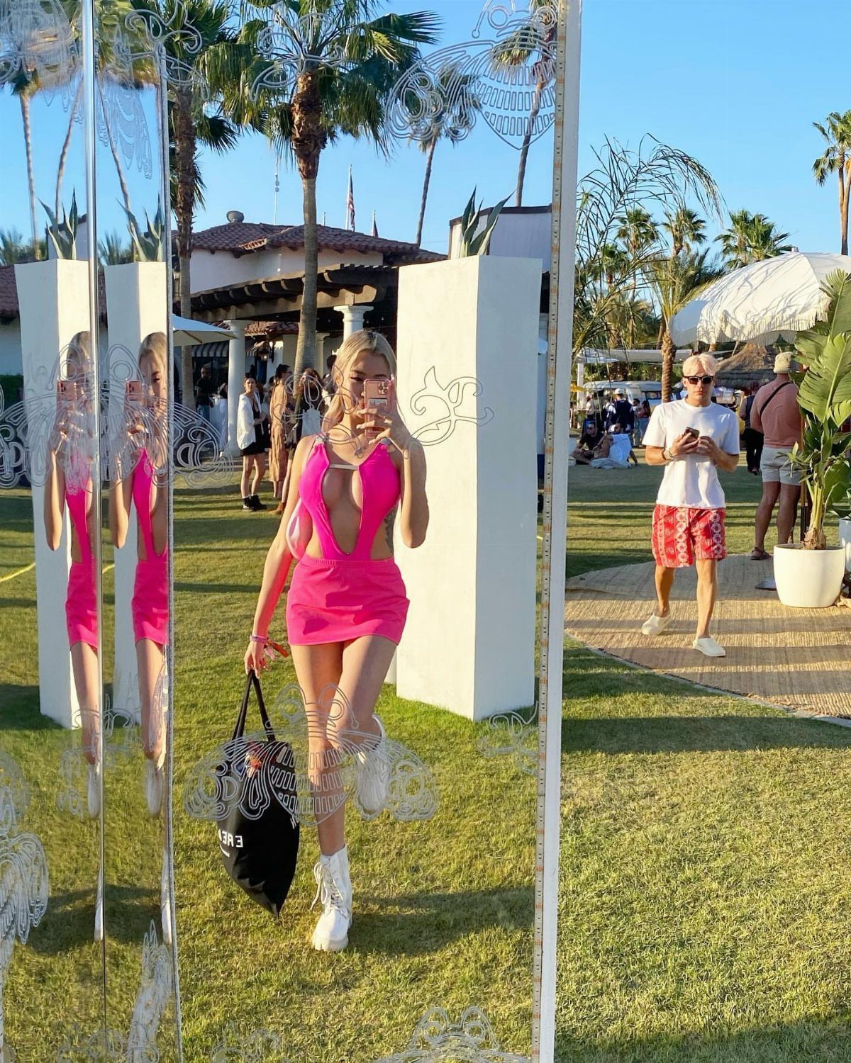 Coachella Outfits for Women: 14 Festival Looks That Work 6 Woman in a pink cutout mini dress taking a selfie in a mirror outdoors.
