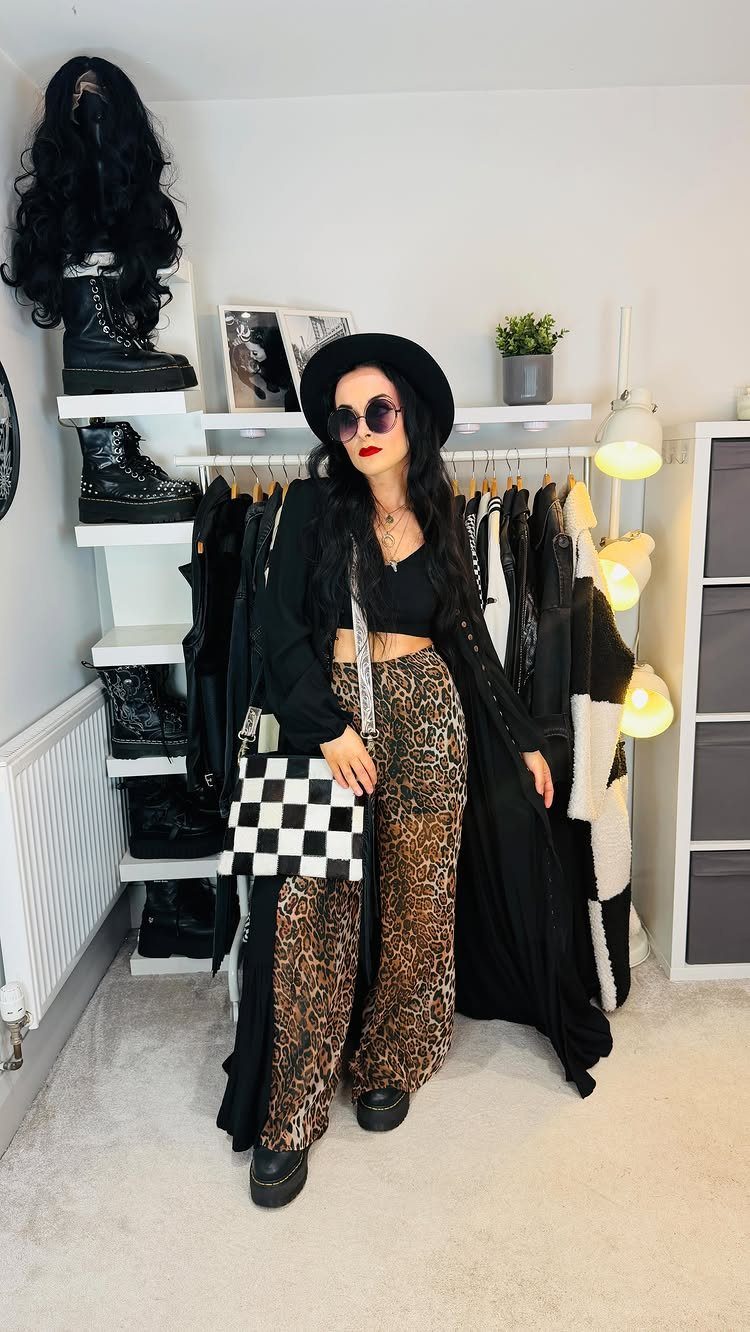 Coachella Outfits for Women: 14 Festival Looks That Work 9 Woman posing in leopard print flared trousers, a black crop top, and a wide-brimmed hat.
