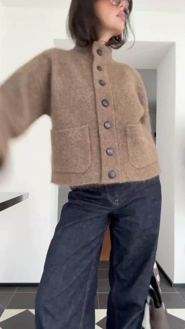 Woman wearing a brown button-up cardigan and wide-leg dark blue denim jeans indoors.