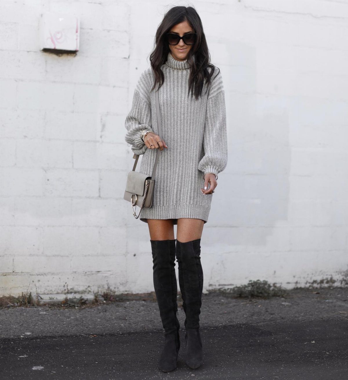Woman in a grey ribbed sweater dress and black knee-high suede boots.