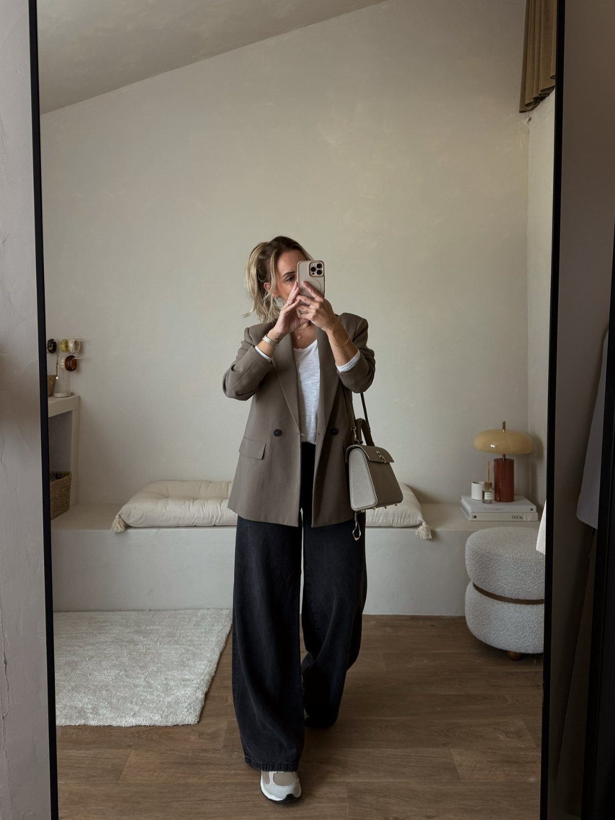 Woman in white t-shirt, wide-leg jeans, and taupe blazer posing for a mirror selfie.
