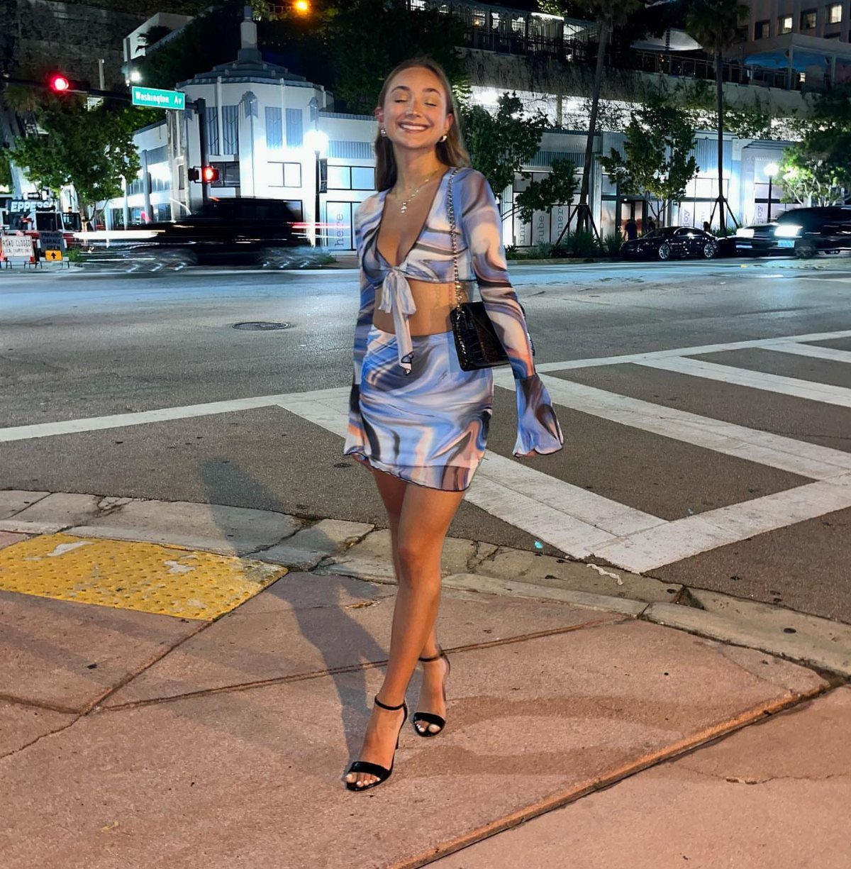 Smiling woman in a blue and white patterned two-piece crop top and mini skirt set.