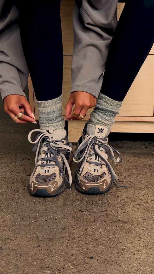 Cute Travel Outfits: 7 Ideas That Balance Style and Comfort 2 Person wearing chunky grey sneakers and ribbed socks with black leggings and a grey jacket.