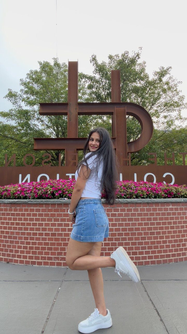 Woman wearing a white tee, denim shorts, and white sneakers posing outdoors.