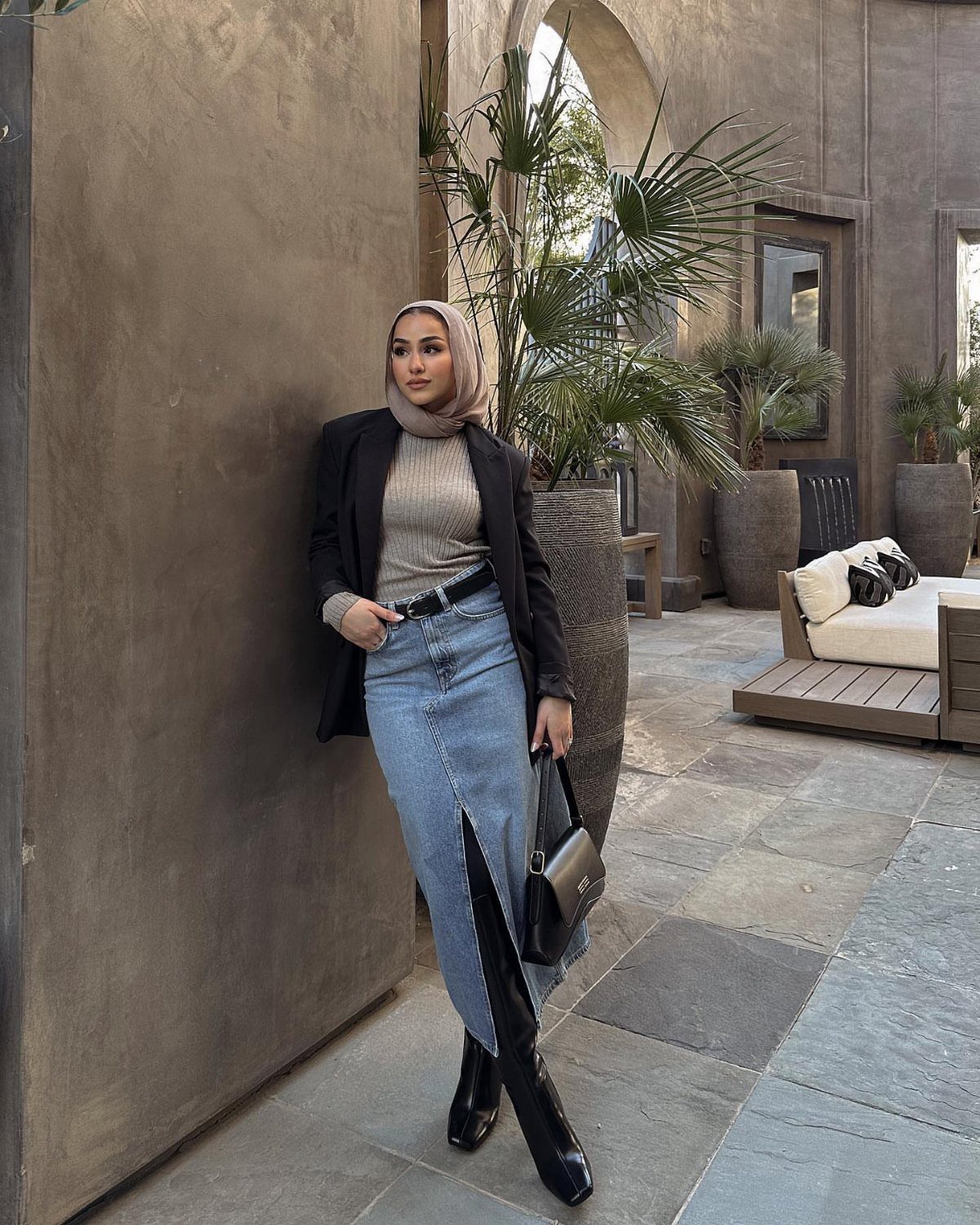 Denim Skirt Outfits: 19 Ways to Style Them This Season 1 Woman in a black blazer and long blue denim skirt posing in a courtyard.
