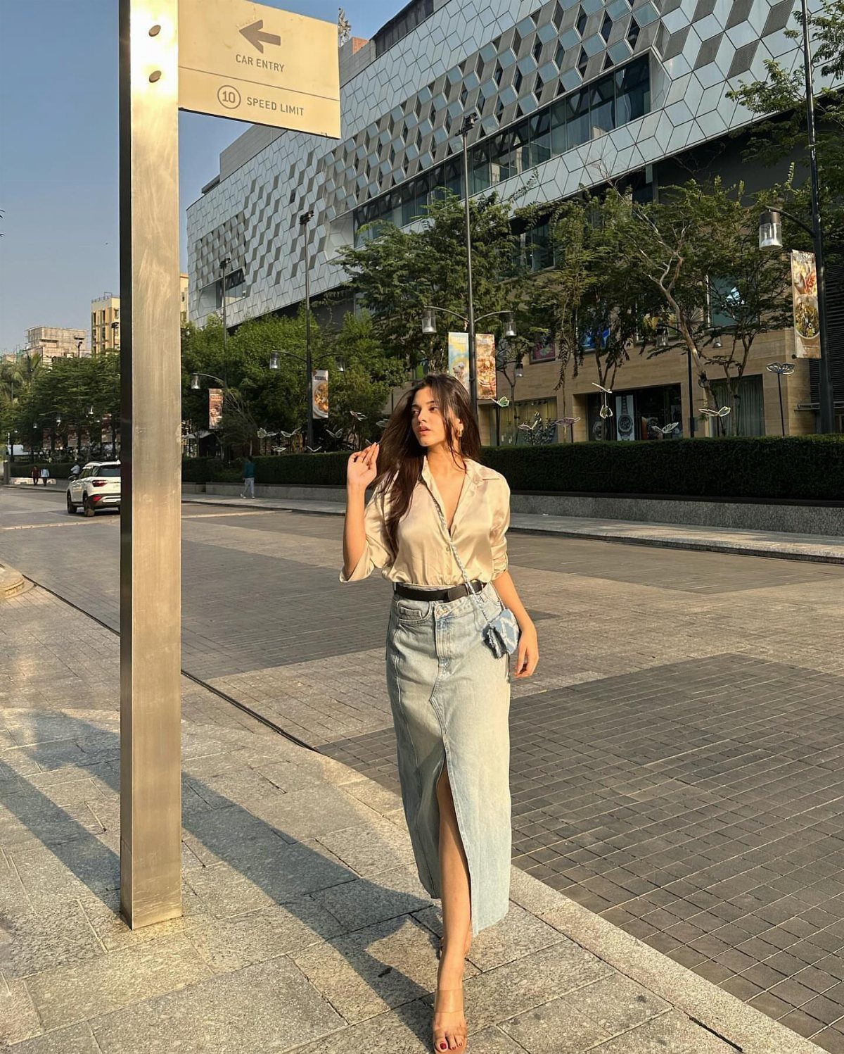 Denim Skirt Outfits: 19 Ways to Style Them This Season 11 Woman wearing a long light-wash denim skirt and a beige button-down shirt.