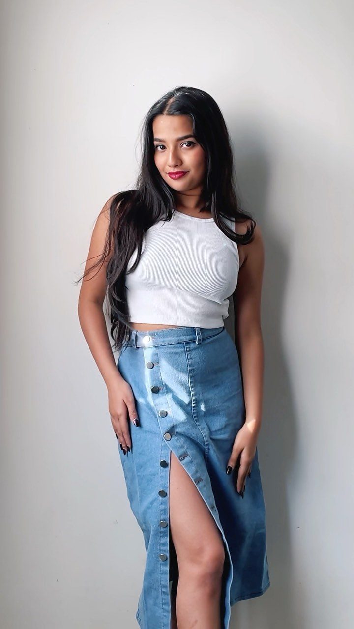 Denim Skirt Outfits: 19 Ways to Style Them This Season 6 Woman wearing a white crop top and blue denim midi skirt with a slit.