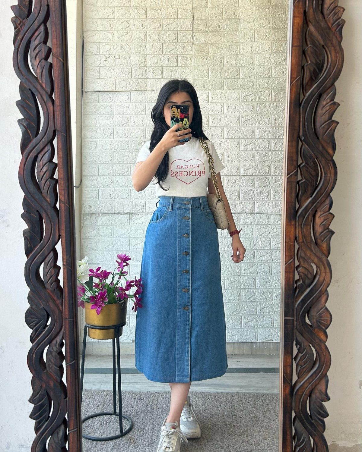 Denim Skirt Outfits: 19 Ways to Style Them This Season 4 Woman wearing a white t-shirt, blue denim midi skirt, and white sneakers.