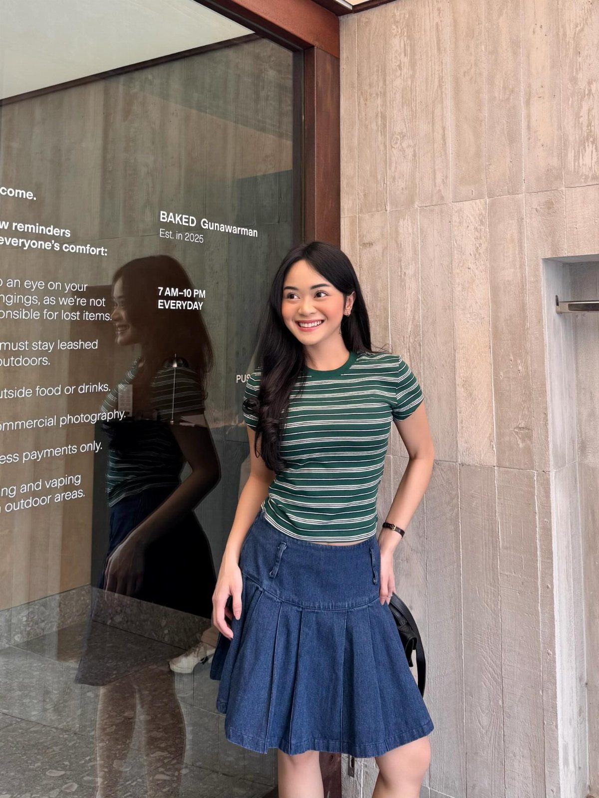 Denim Skirt Outfits: 19 Ways to Style Them This Season 16 Woman wearing a green striped shirt and a dark blue denim mini skirt.