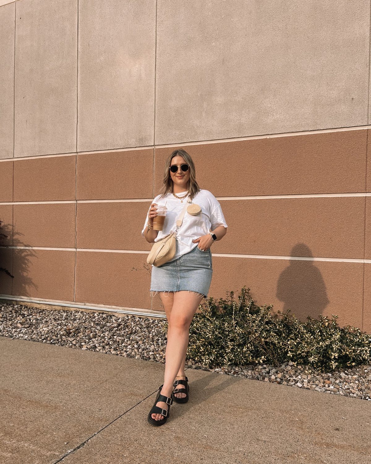 Denim Skirt Outfits: 19 Ways to Style Them This Season 18 Woman in white t-shirt and denim mini skirt with straw bag and sandals.