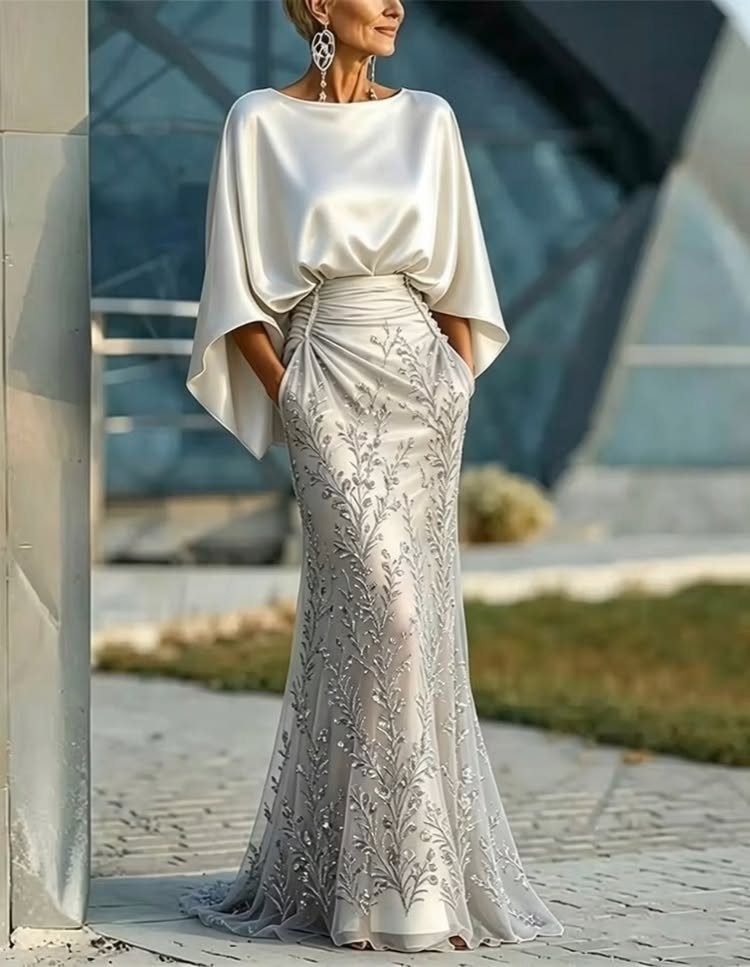 Woman in a champagne evening gown with a satin cape and embroidered skirt.