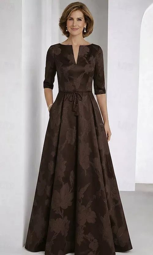 Woman wearing a chocolate brown fit-and-flare gown with a cinched waist and floral pattern.