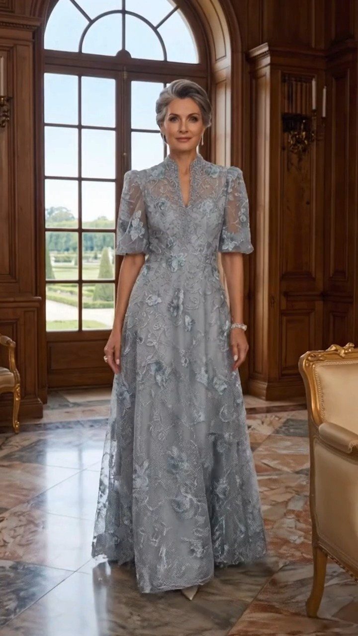 Mature woman with grey hair wearing a light blue lace floor-length evening gown.
