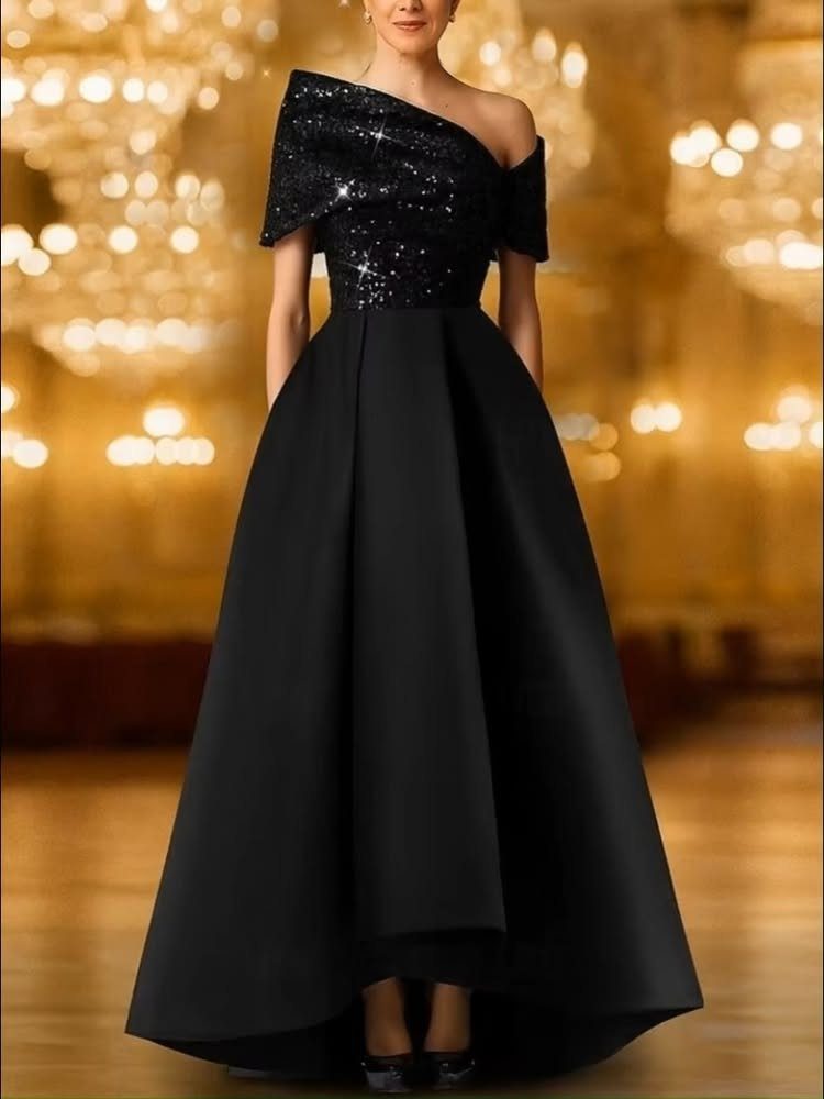 Woman in a black one-shoulder evening gown with a sequined bodice in a ballroom